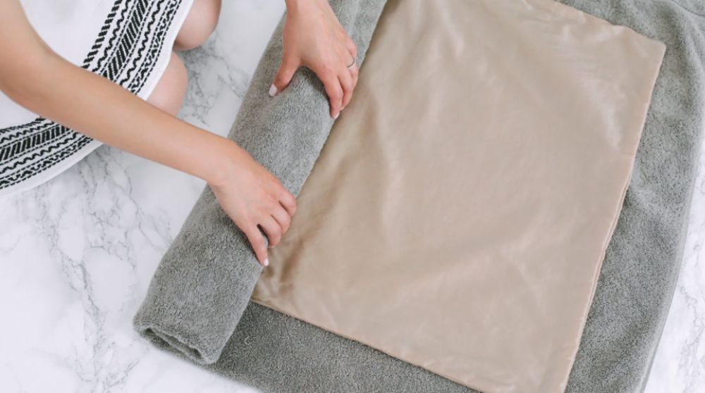 đặt quần áo ướt lên khăn bông. Gấp khăn lại và thấm nhẹ